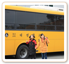 버스 앞에서 두 명의 학생이 정면을 바라보고 서 있는 모습